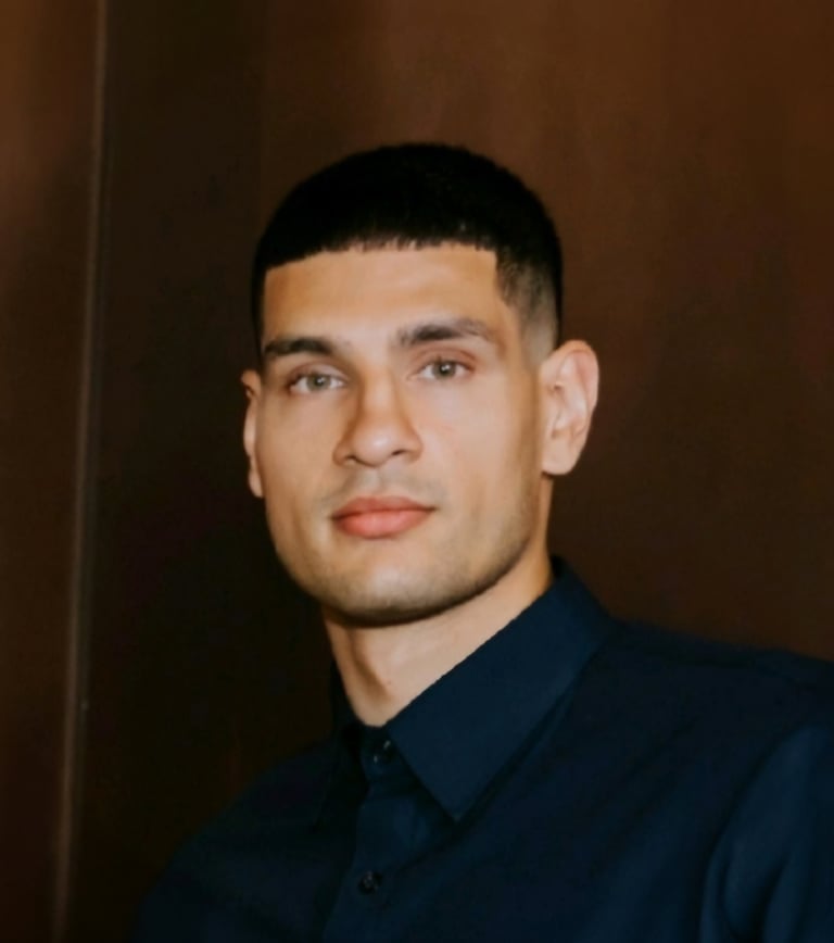 Headshot of a man with short dark hair wearing a dark navy button-up shirt against a brown background